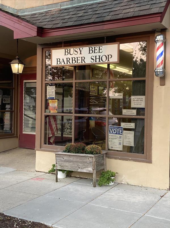 The Busy Bee Barber Shop storefront on Main Street, with its sign over the window and a barber pole