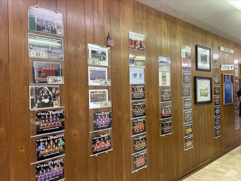The shop’s wood-paneled wall, lined with park district team photos